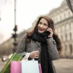 Zadowolona kobieta z kolorowymi torbami w ręku wracająca z zakupów z personal shopperem